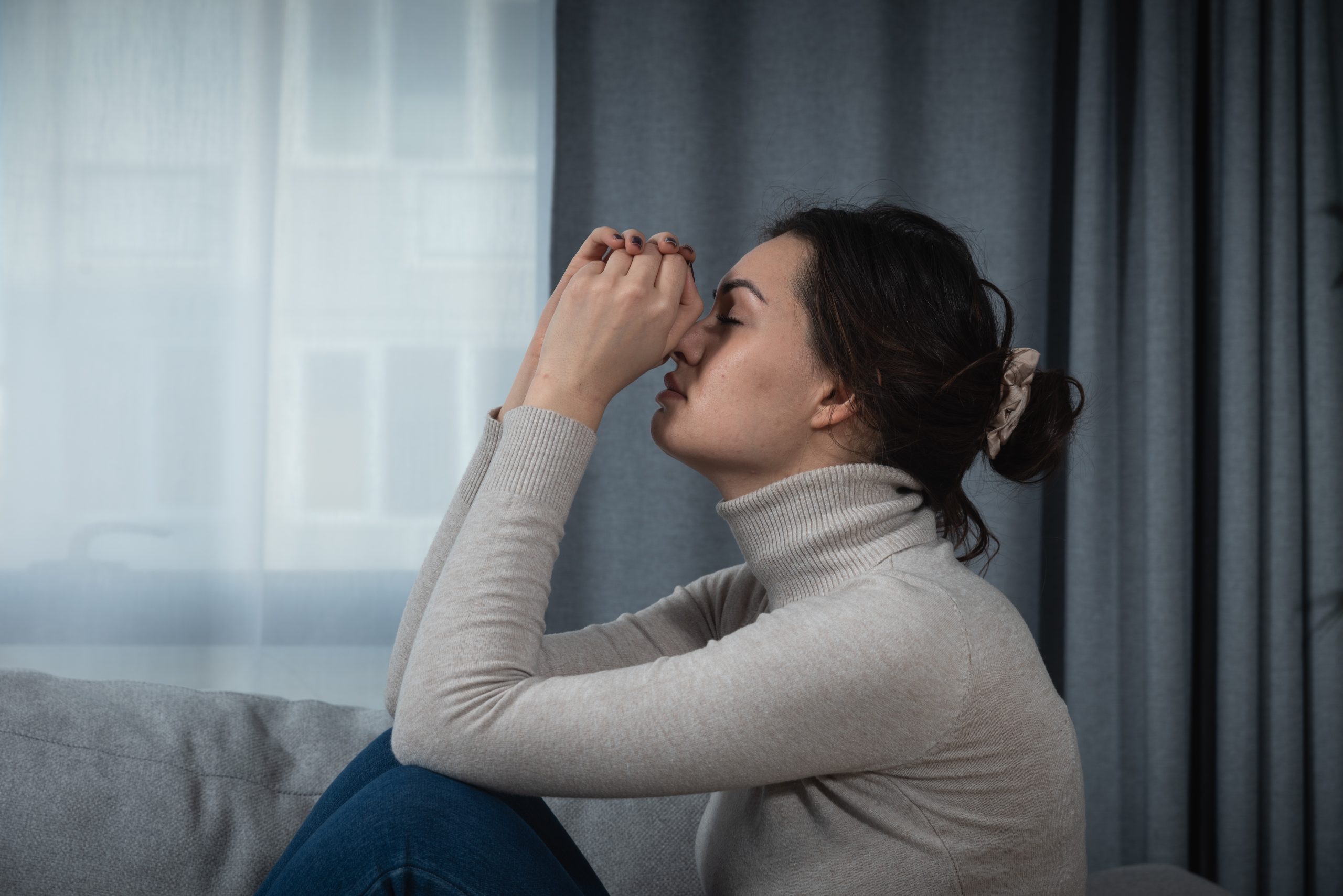 Young sad woman with broken heart sitting alone at home suffering from depression anxiety and bad mental condition. Female having hard time and burnout of overthinking and worry