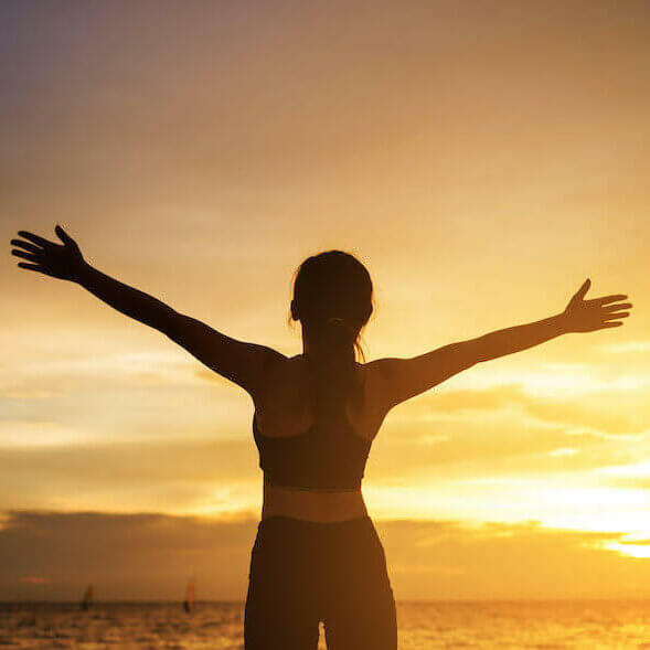 happy young woman enjoying freedom with open hands at sunset. young woman christian worship concept.